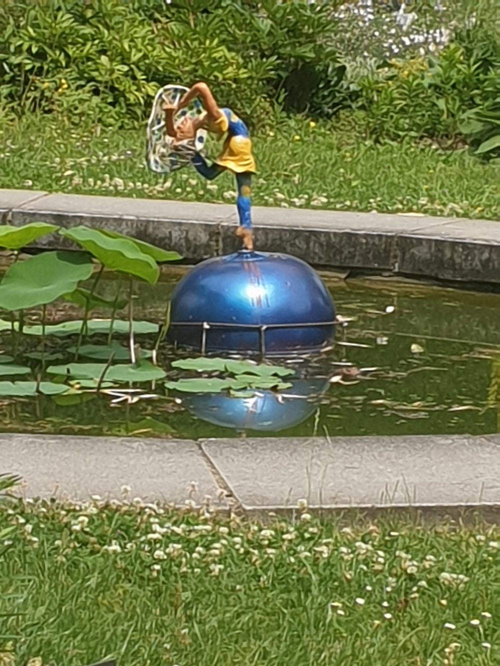 Kleine Figur einer Tänerzin auf einer Kugel im Teich