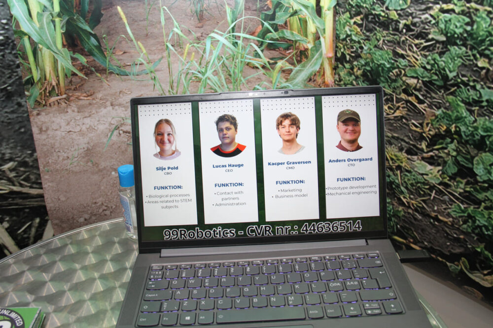 Blick auf den Laptop und die vier Dän:innen der Junior Company, die gemeinsam mit sambischen Kolleg:innen die Idee in einem Ferien-Workshop entwickelt haben