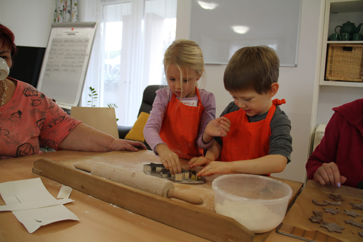 Kindergartenkinder zu Besuch bei AWIK - hier backen sie mit älteren Menschen Kekse bzw. stechen sie aus dem Teig aus