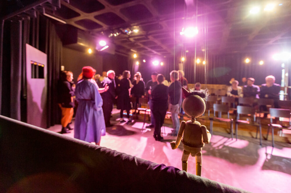 Pinocchio - und der Fotograf - blicken von der Bühne aus auf das Treiben nach der Premiere im Publikumsraum