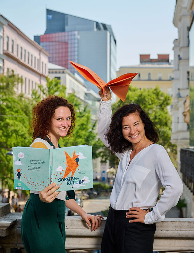 Illustratorin Sonja Stangl mit Buch und Autorin Magda Hassan mit einem aus Papier gefaltetem Schmetterling