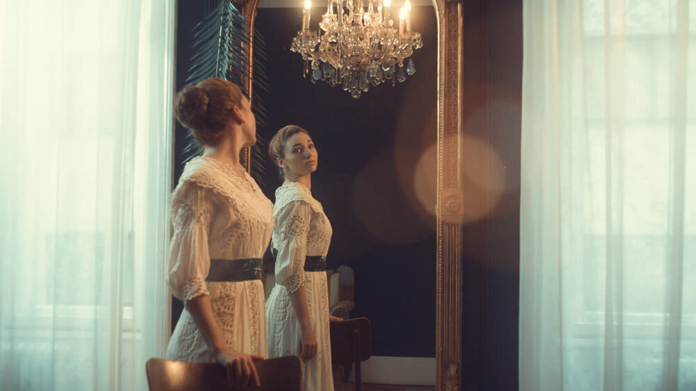 Bild aus dem Film: Darstellerin der jungen Eugenie Schwarzwald vor einem Spiegel