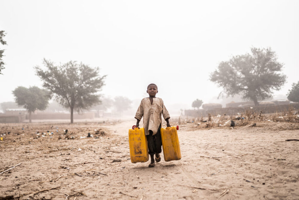 Hier schleppt ausnahmsweie einmal ein Bub (im Niger) zwei schwere, volle Wasserkanister