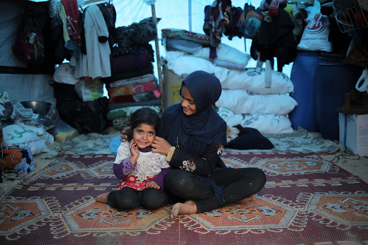 Die 14-jährige Duha sitzt neben ihrer 3-jährigen Schwester Malak in ihrem Zelt in Rafah, südlich des Gazastreifens. Duha ist gehörlos, erhält Unterstützung von Unicef in Palästina und verwendet Gebärdensprache, um sich auszudrücken und über ihre Erfahrungen während des anhaltenden Krieges zu sprechen.