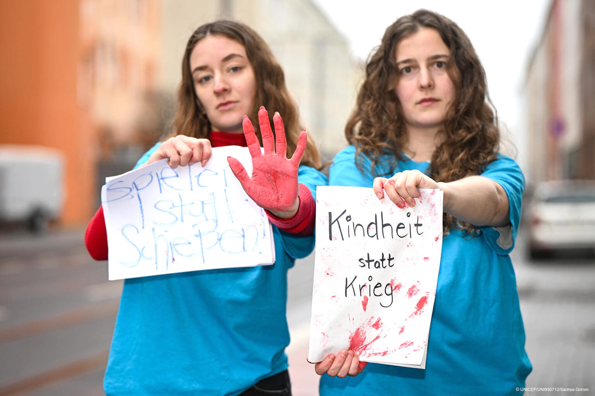 Zwei Unicef-Mitarbeiterinnen mit Plakaten zum Red Hand Day