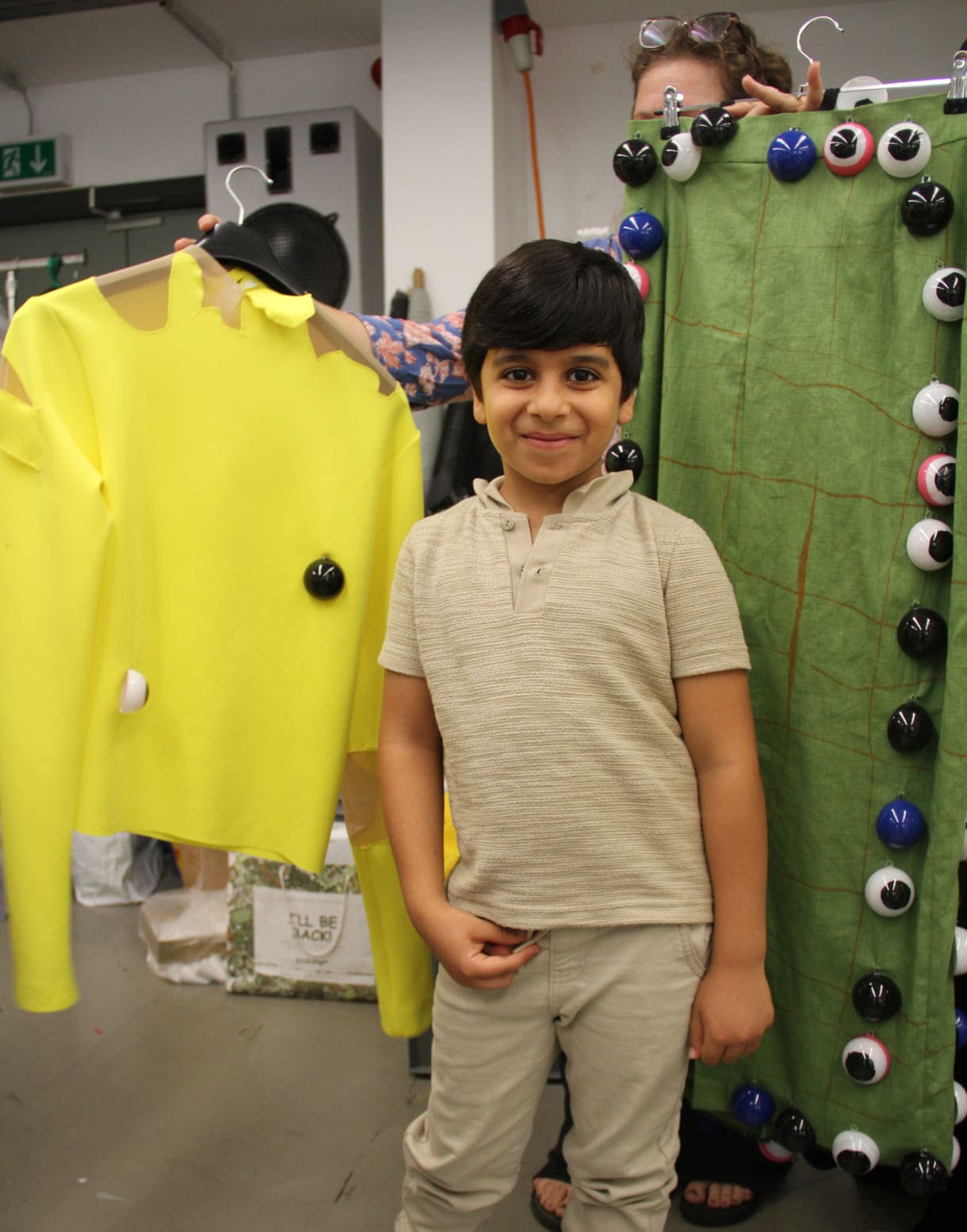 Abduallah Al Ibrahim (7) vor den Stoff gewordenen Kleidungsteilen seines gezeichneten Entwurfs