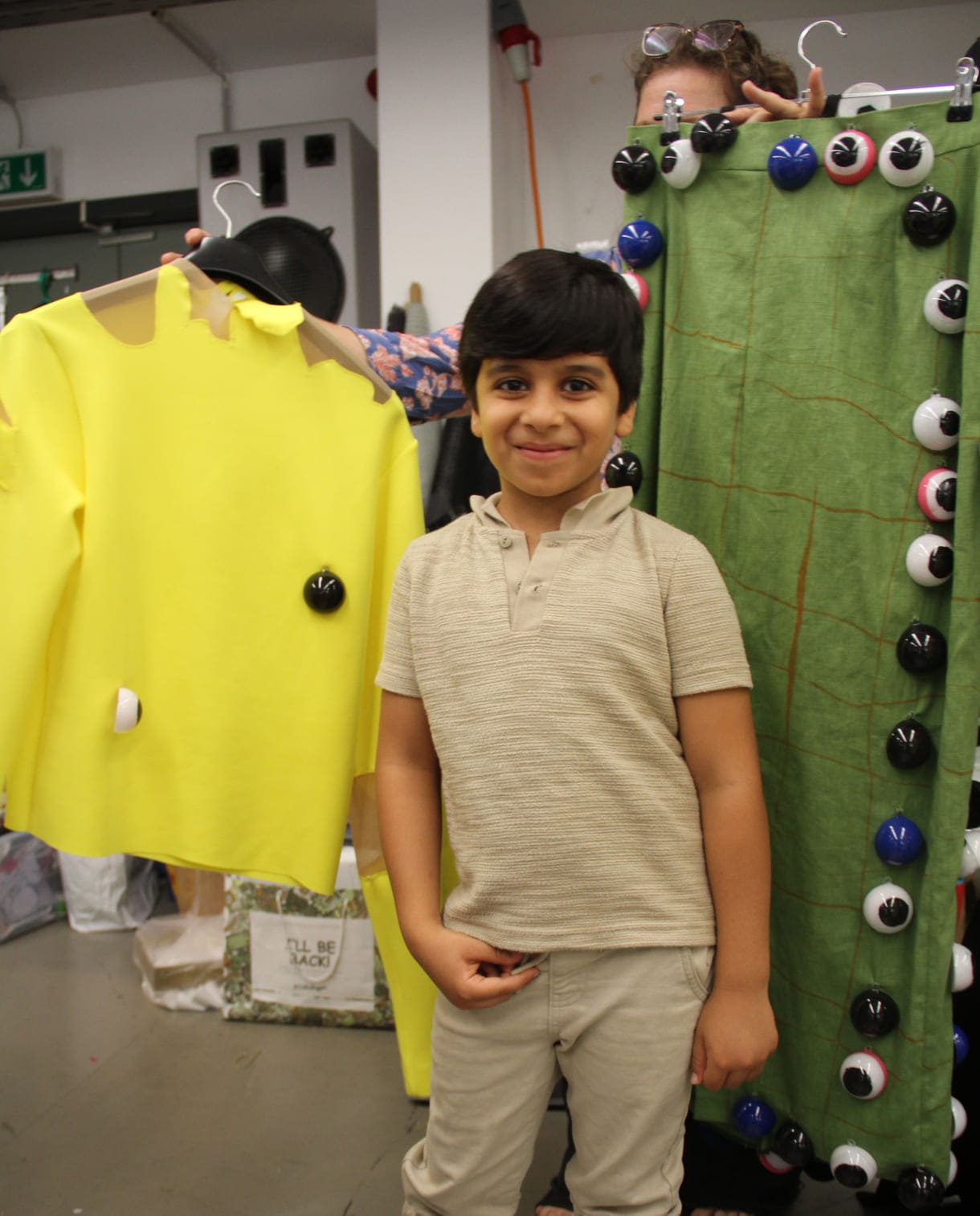 Abduallah Al Ibrahim (7) vor den Stoff gewordenen Kleidungsteilen seines gezeichneten Entwurfs