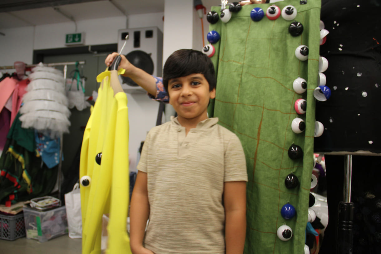 Abduallah Al Ibrahim (7) vor den Stoff gewordenen Kleidungsteilen seines gezeichneten Entwurfs