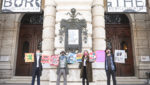 Vier Menschen vor dem geschlossenen Burgtheater. Sie halten Tafeln auf denen sie die Öffnung von Kunst und Kultur als erste nach dem Lockdown fordern