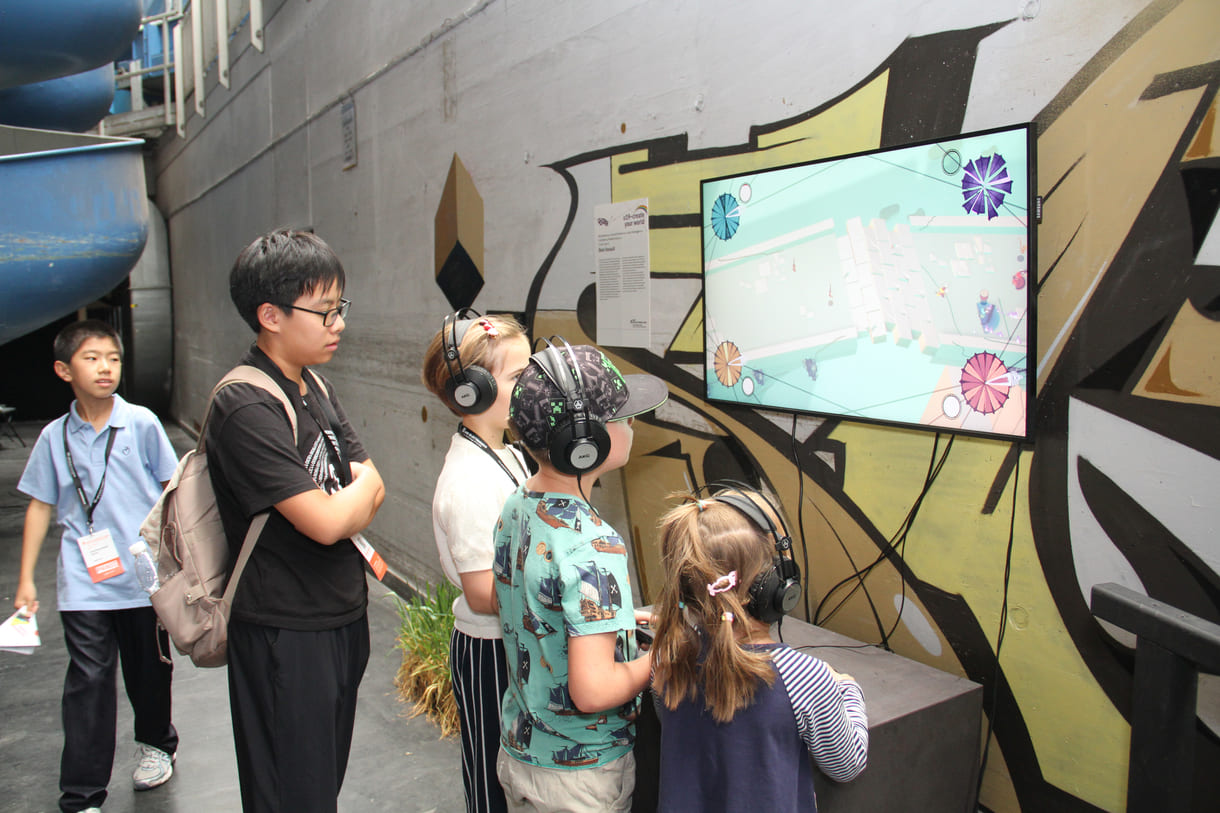 Besucher:innen spielen das Musik-Video-Game "Beat Aussault" in der U19-Ausstellung