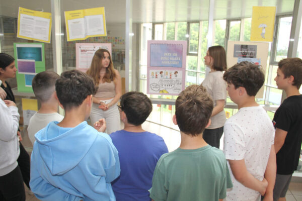 Jugendliche begleiten jüngere Schüler:innen durch die selbst gestaltete Antirassismus-Ausstellung