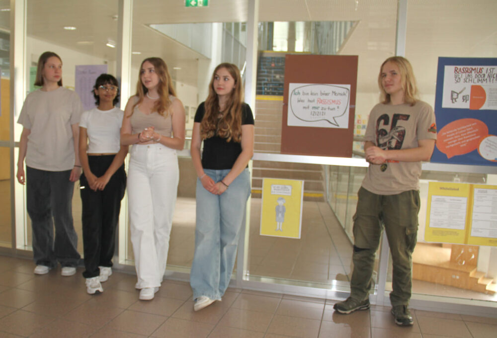Jugendliche begleiten jüngere Schüler:innen durch die selbst gestaltete Antirassismus-Ausstellung