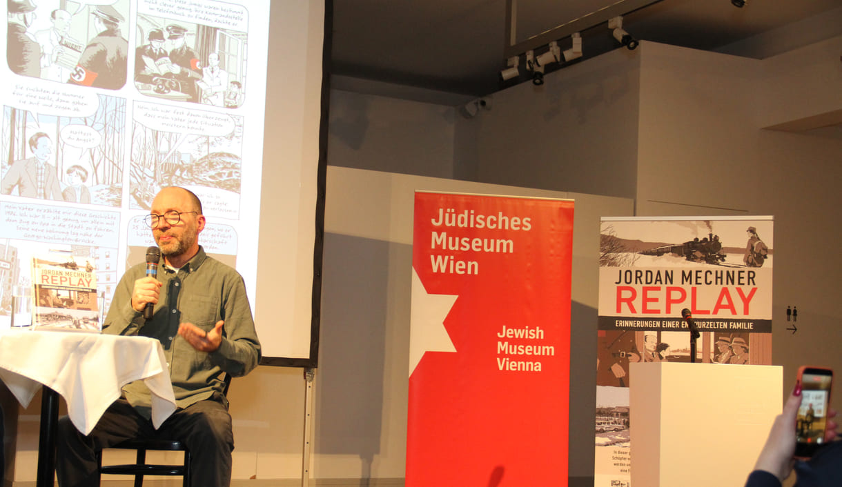 Jordan Mechner mit eingeblendeten Buchseiten im Hintergrund; im Vordergrund ein Smartphone mit dem gefilmt wird