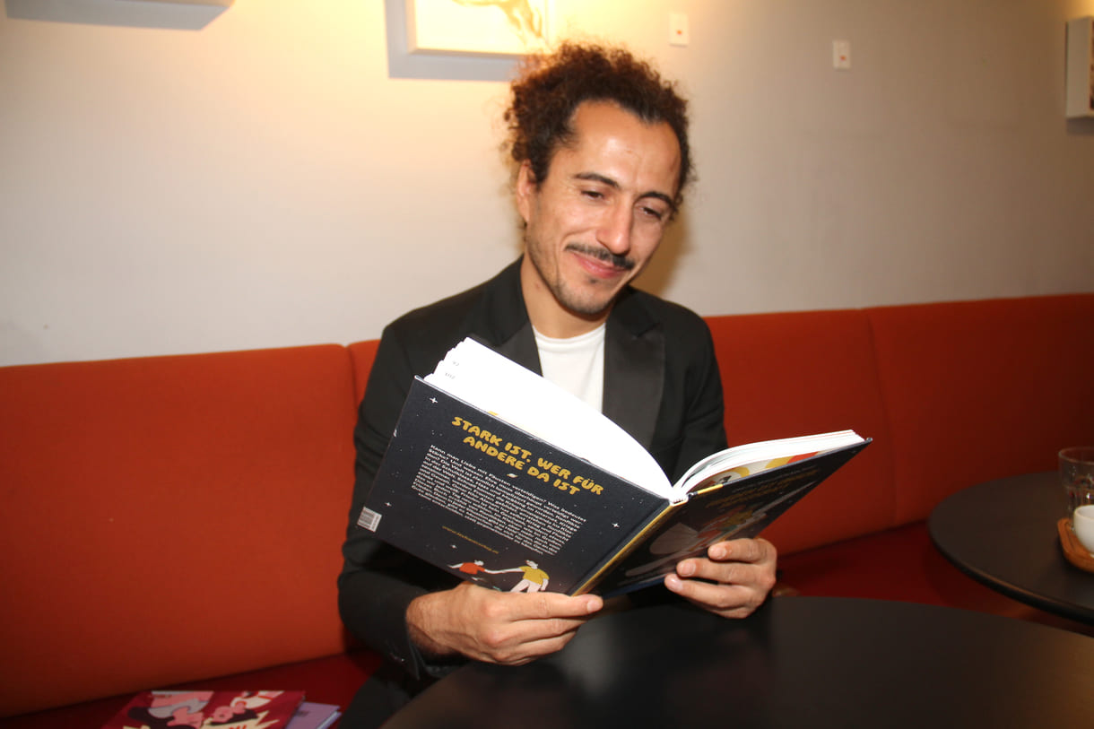 Autor Omar Khir Alanam mit dem offenen Buch "Frieden ist unsere Superkraft"
