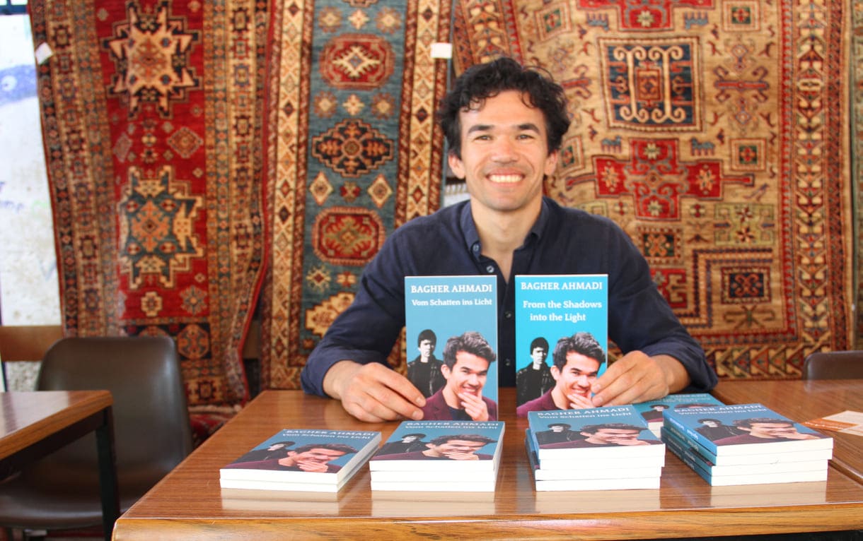 Schauspieler Bagher Ahmadi mit seinem Buch auf Deutsch und Englisch