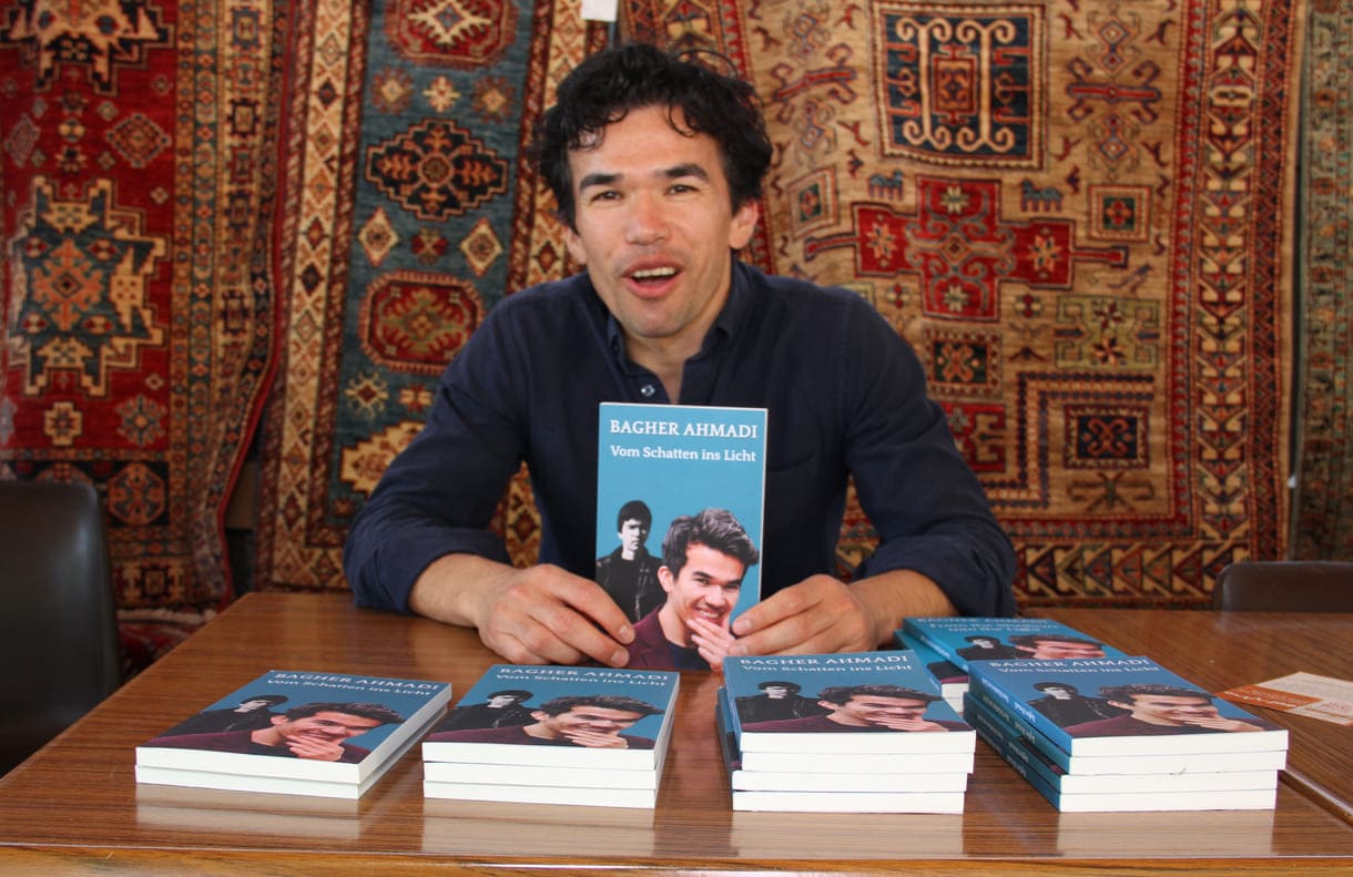 Schauspieler Bagher Ahmadi mit seinem Buch auf Deutsch und Englisch