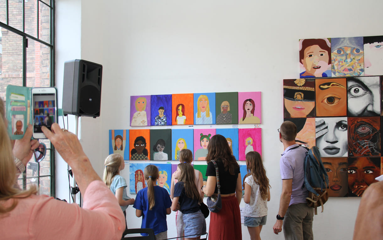 Besucher:innen einer Galerie mit dicht behängten Wänden