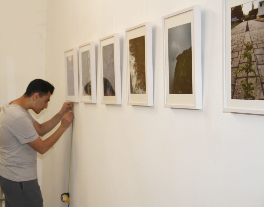 Der junge Fotograf Omran Almasri beim Hängen der Bilder und der Beschriftungen