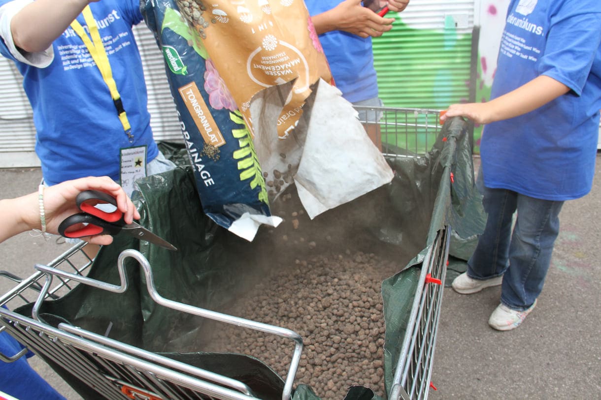 Kinder befüllen den Einkaufswagen mit Granulat und Erde