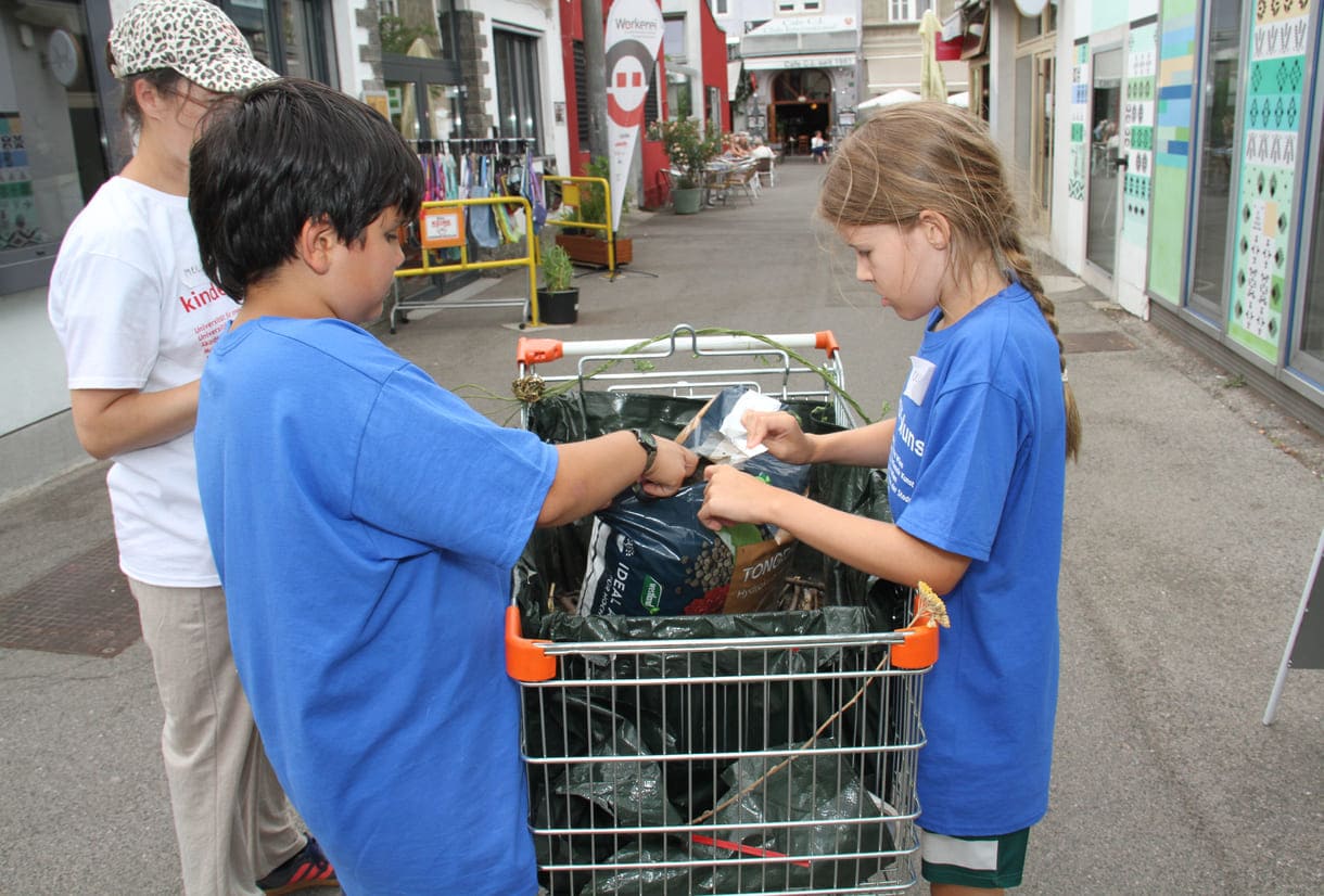 Kinder befüllen den Einkaufswagen mit Granulat und Erde