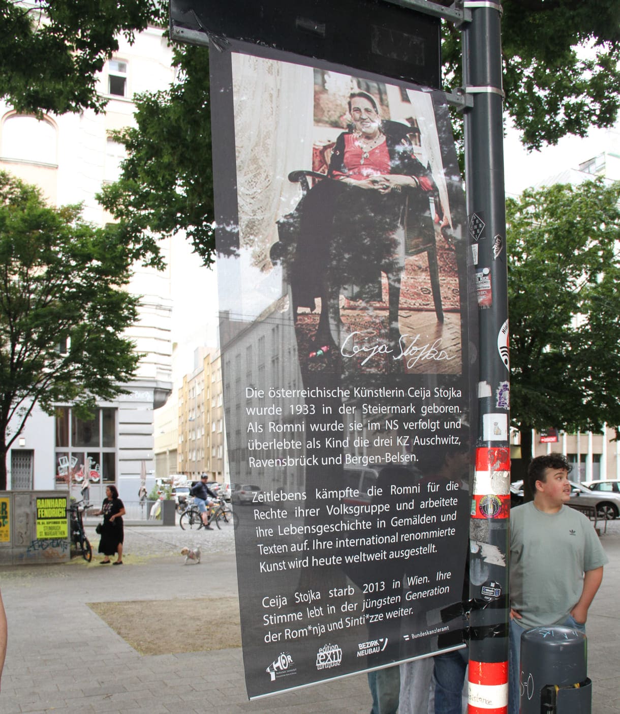 Unter dem Platzschild ein Banner mit Infos zur Namensgeberin Ceija Stojka