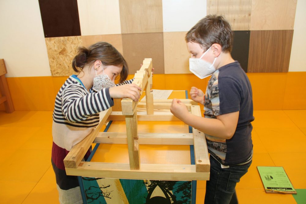 Kinder puzzlen das Modell eines Dachstuhls zusammen