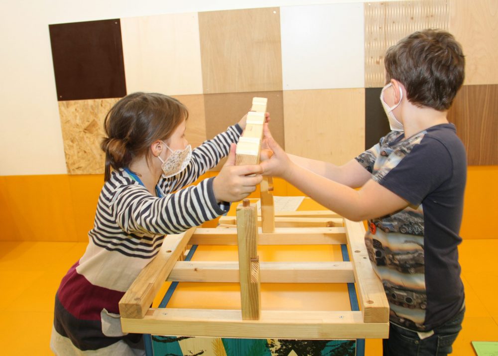 Kinder puzzlen das Modell eines Dachstuhls zusammen
