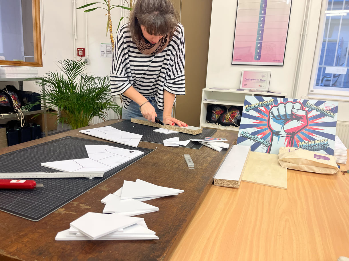 Teresa Bauer, eine von vier Mitarbeiter:innen der Fachstelle Demokratie, schneidet eigenhändig die Teile für die Puzzles