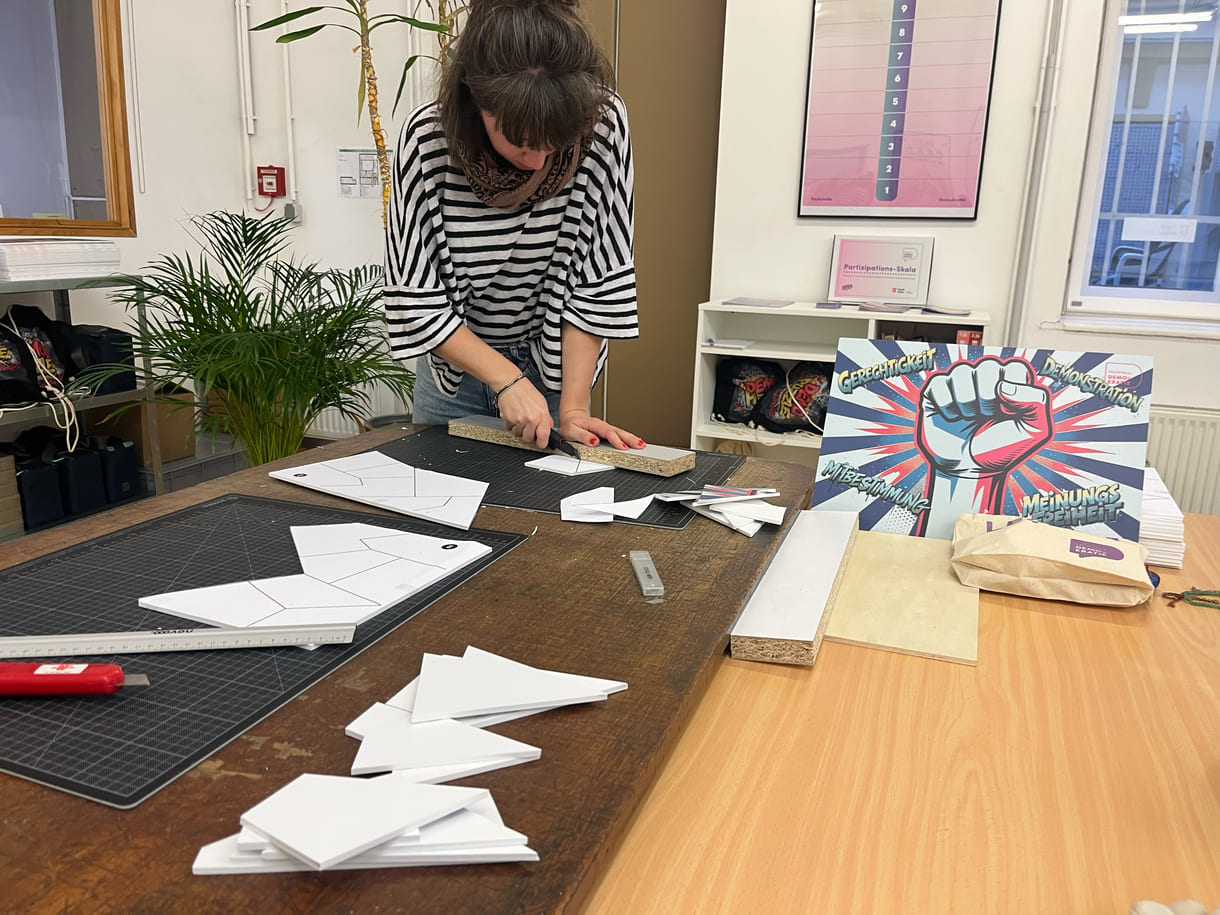 Teresa Bauer, eine von vier Mitarbeiter:innen der Fachstelle Demokratie, schneidet eigenhändig die Teile für die Puzzles