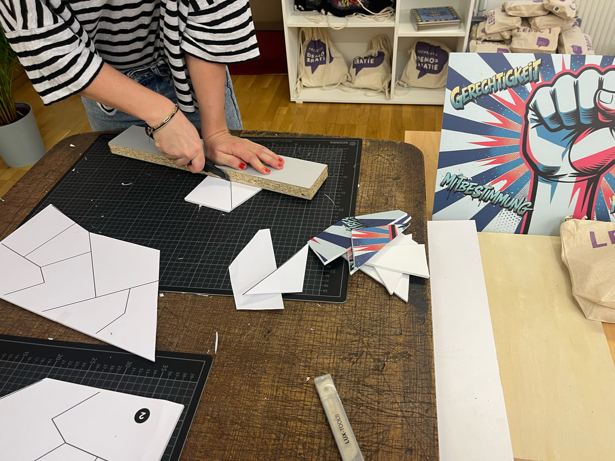 Teresa Bauer, eine von vier Mitarbeiter:innen der Fachstelle Demokratie, schneidet eigenhändig die Teile für die Puzzles