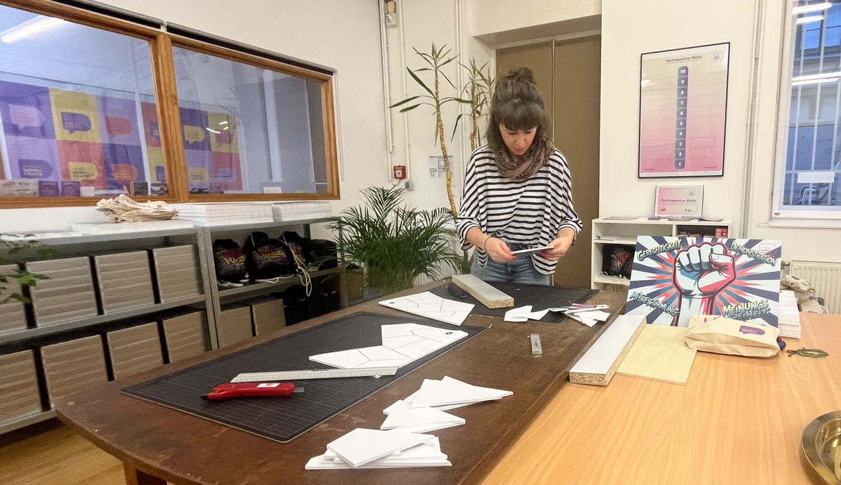 Teresa Bauer, eine von vier Mitarbeiter:innen der Fachstelle Demokratie, schneidet eigenhändig die Teile für die Puzzles