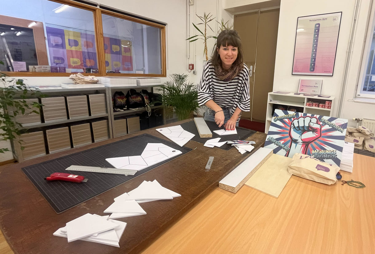 Teresa Bauer, eine von vier Mitarbeiter:innen der Fachstelle Demokratie, schneidet eigenhändig die Teile für die Puzzles