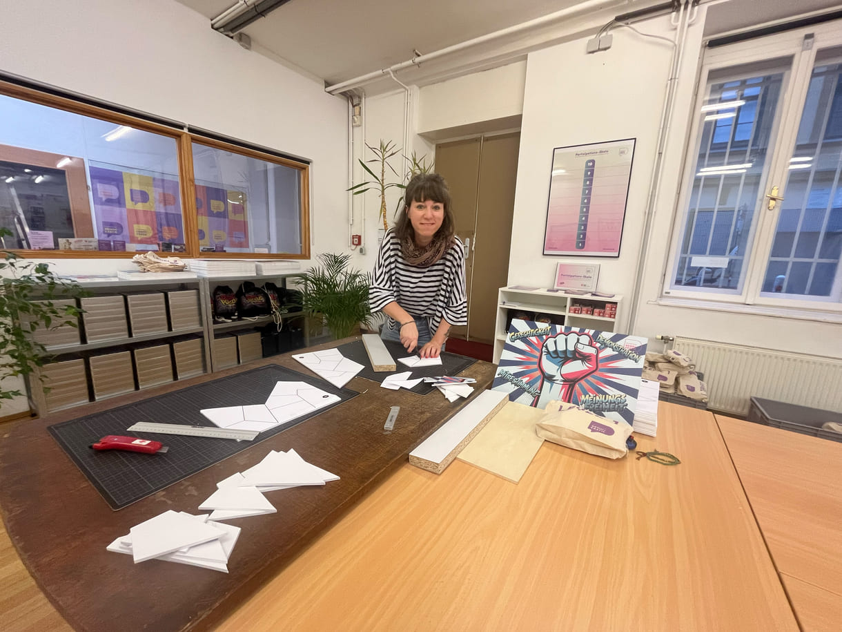 Teresa Bauer, eine von vier Mitarbeiter:innen der Fachstelle Demokratie, schneidet eigenhändig die Teile für die Puzzles