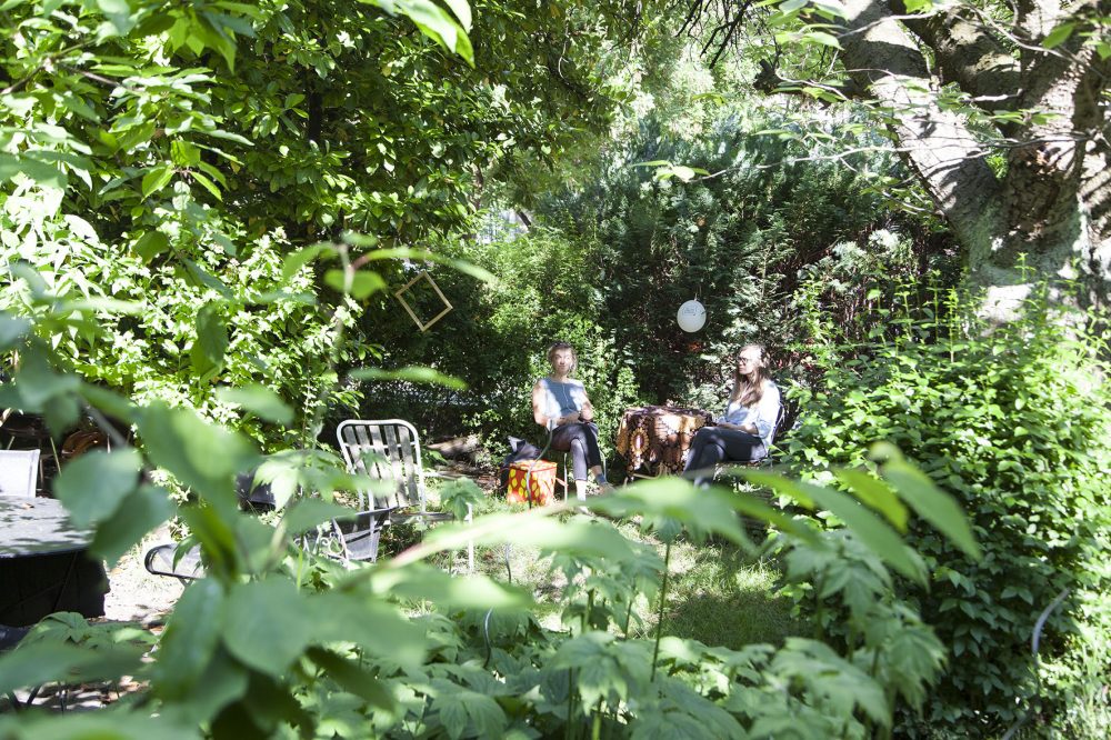 Zuhörer*innen auf Erzählstühlen in einem Garten