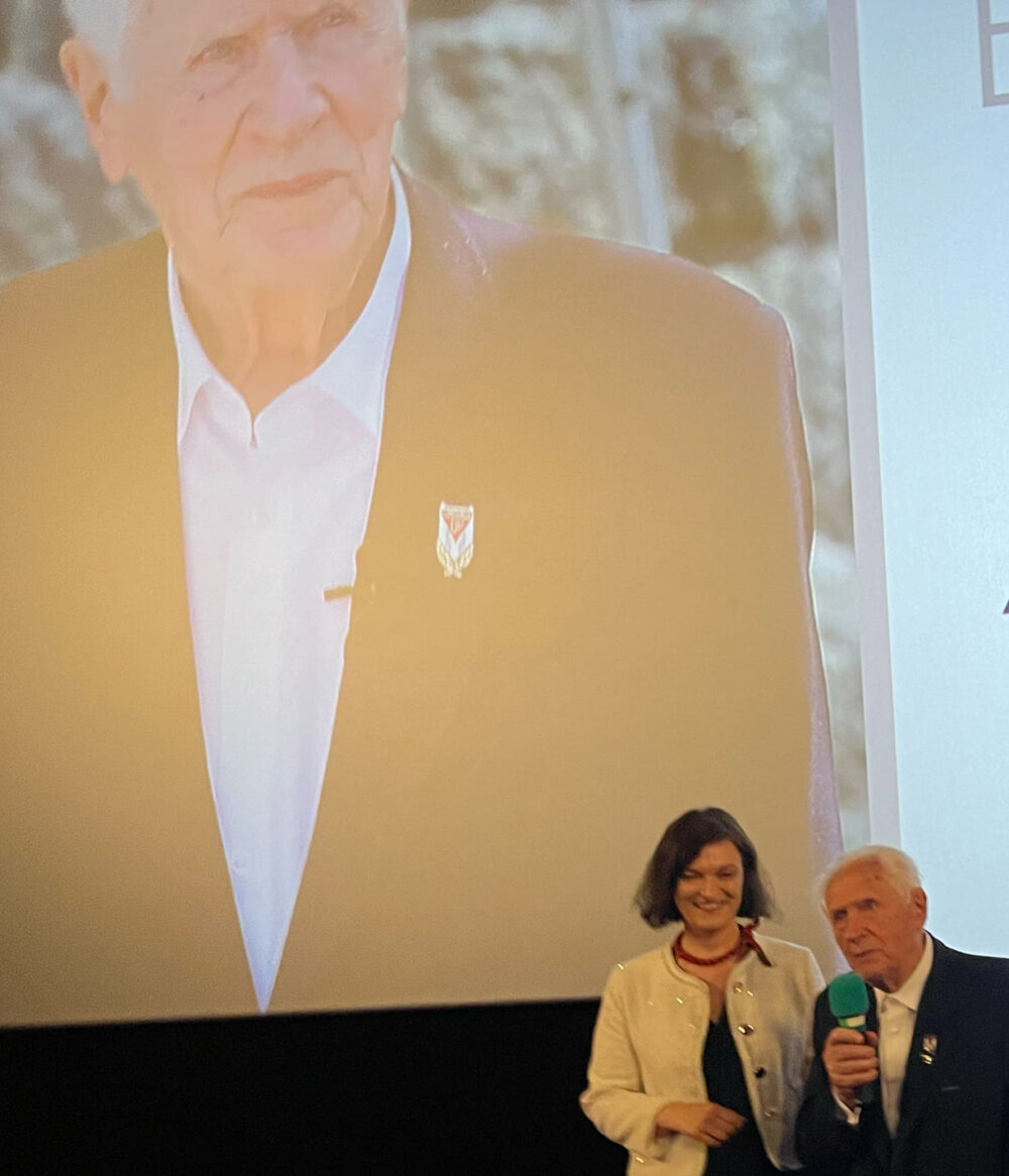 Magdalena Żelasko und Stanisław Zalewski im Kinosaal - im Hintergrund ein Bild aus dem Film sowie die Sponsor:innen