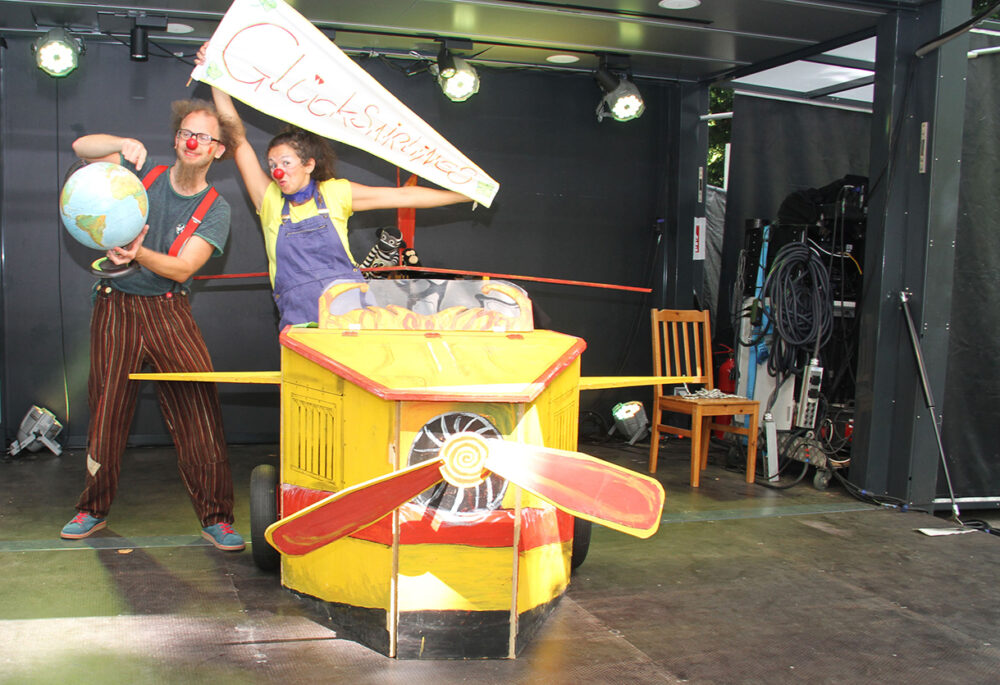 Eva Zarbl (rechts) und Andi Geyer (links) als Clownin Paula und Clown Fu mit ihrem hölzernen Flugzeug und einem Globus des Stücks 