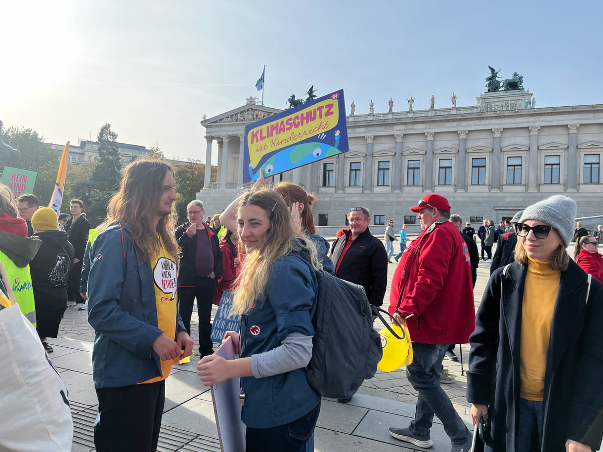 Einige Teilnehmer:innen mit Plakatenvor dem Parlament