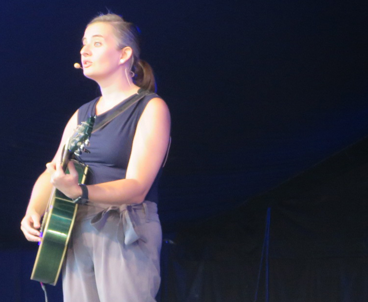 Kabarettistin Elli Bauer mit Gitarre auf der Bühne im Schwechater Felmayergarten