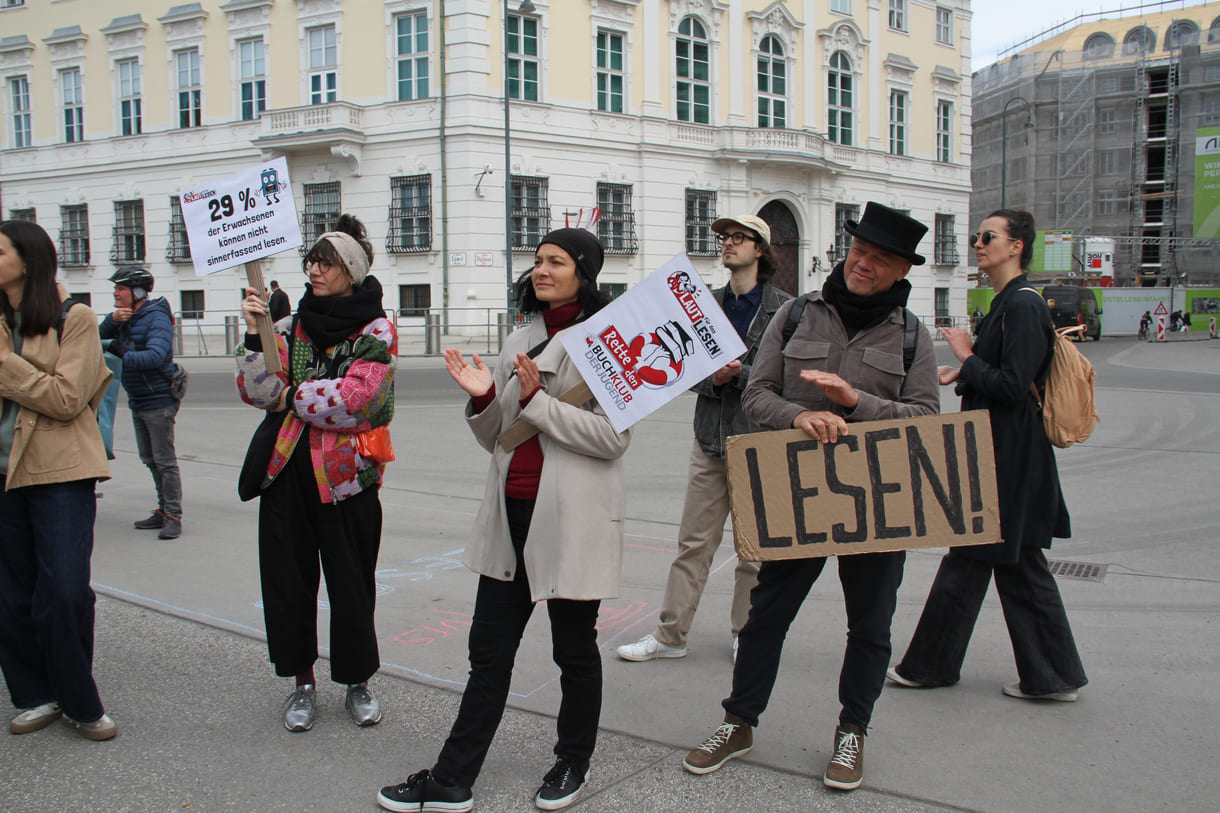 Demonstrant:innen mit Sprüchen auf Kartontafeln
