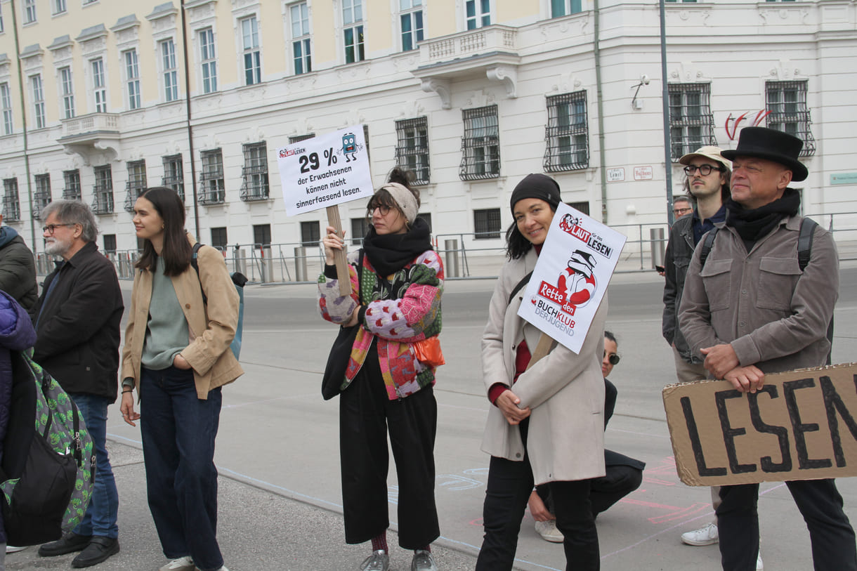 Demonstrant:innen mit Sprüchen auf Kartontafeln