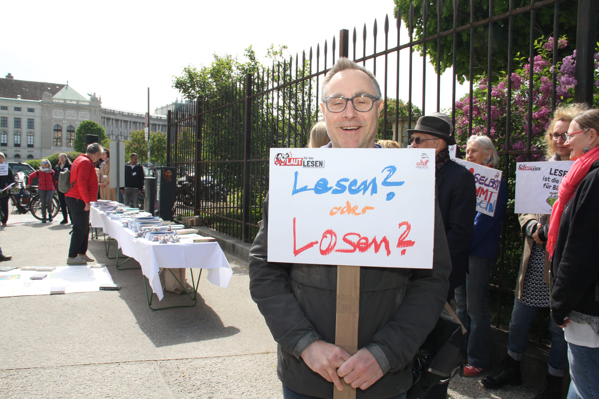 Demonstrant:innen mit Sprüchen auf Kartontafeln