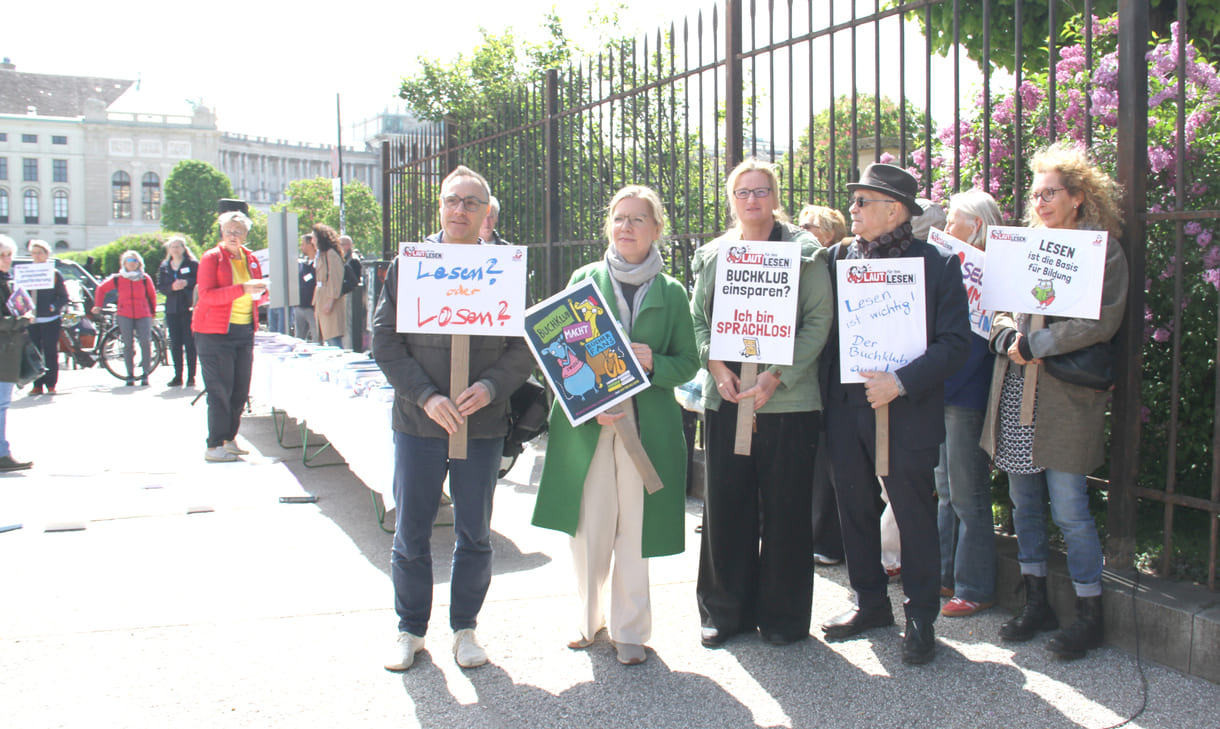 Demonstrant:innen mit Sprüchen auf Kartontafeln