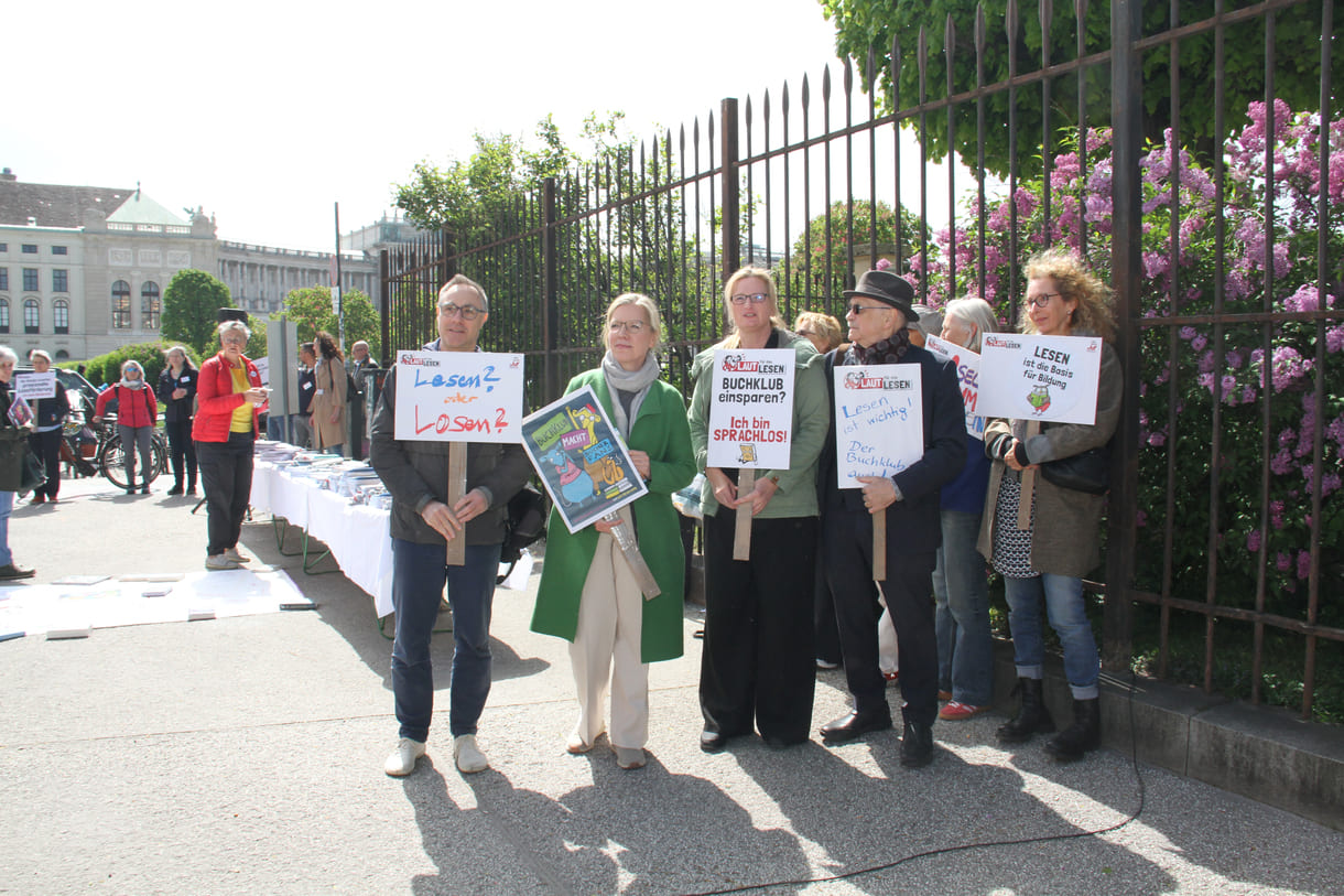 Demonstrant:innen mit Sprüchen auf Kartontafeln