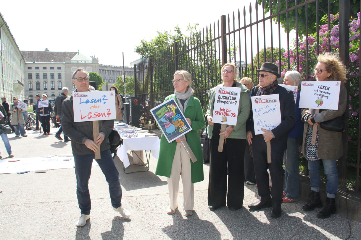 Demonstrant:innen mit Sprüchen auf Kartontafeln