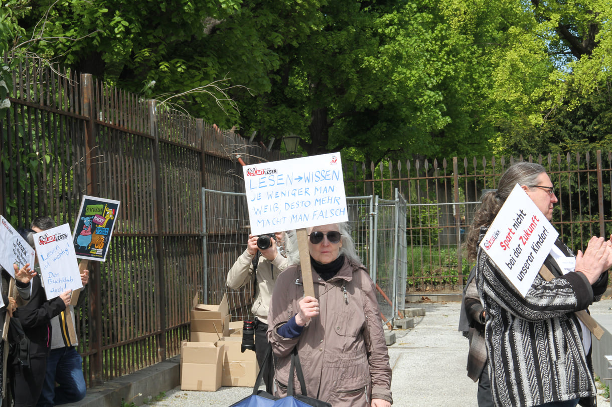Demonstrant:innen mit Sprüchen auf Kartontafeln