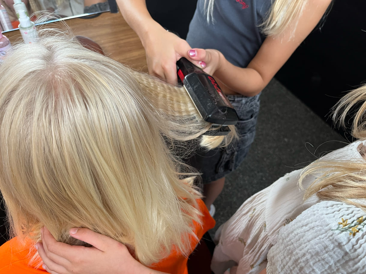 Kinder als Kund:innen sowie als Friseur:innen am Werk