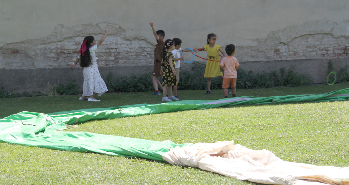 Spielende Kinder neben der Umrandung des Fußball-Feldes, die noch auf die Luftfüllung wartet