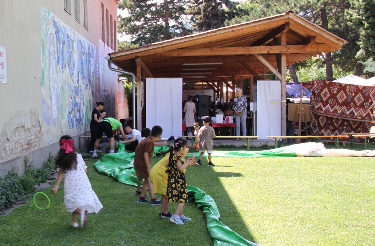 Spielende Kinder neben der Umrandung des Fußball-Feldes, die noch auf die Luftfüllung wartet