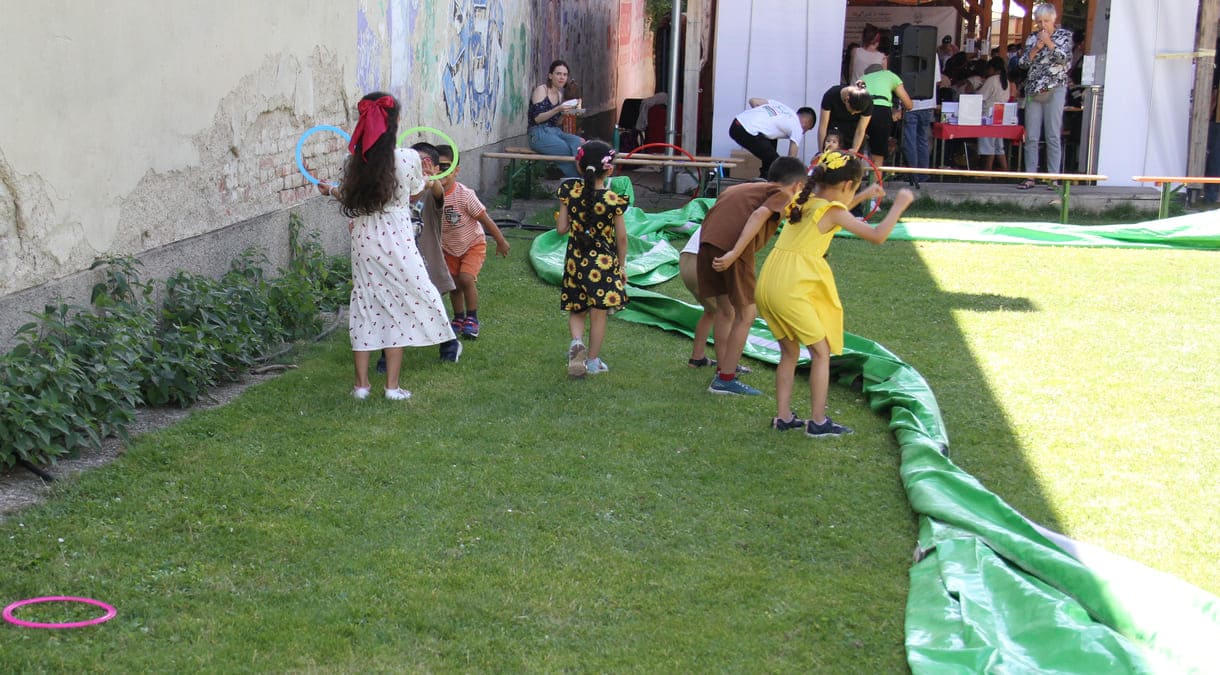 Spielende Kinder neben der Umrandung des Fußball-Feldes, die noch auf die Luftfüllung wartet