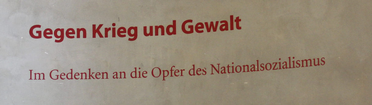 Aufschrift an einer Aula-Wand: Gegen krieg und Gewalt - Im Gedenken an die Opfer des Nationalsozialismus